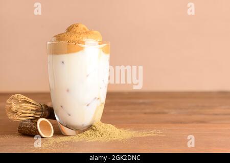 Ein Glas schmackhafter dalgona hojicha, Chasen und Pulver auf dem Tisch Stockfoto
