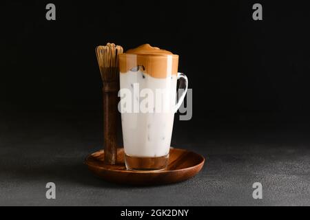 Glas Tasse leckeren dalgona hojicha Latte und Chasen auf dunklem Hintergrund Stockfoto