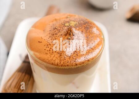 Ein Glas leckeren dalgona hojicha Latte auf grauem Hintergrund, Nahaufnahme Stockfoto