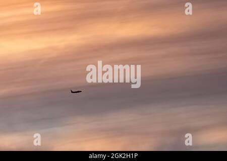 Doppeldecker, die hoch oben am Himmel flogen, schilhouetteten vor einem Sonnenuntergang Stockfoto