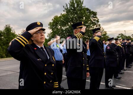 BLOOMINGTON, INDIANA - 11. SEPTEMBER: Feuerwehrleute grüßen, während die amerikanische und die Indiana-Flagge während des 20. Jahrestages der Gedenkfeier des 11. September am 11. SEPTEMBER 2021 bei Ivy Tech in Bloomington, Indiana, angehoben werden. Vor zwanzig Jahren griffen Terroristen am 11. September 2001 die Vereinigten Staaten an und töteten über 2000 Menschen im World Trade Center in New York, New York, und begannen einen Krieg mit den Vereinigten Staaten, der andauert. Stockfoto