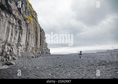 Panoramablick auf die Reynisfjara Beach Cave in Island mit großen Basaltsäulen und felsigen Strand. Kalter Windiplatz am Strand mit großen Wellen. Stockfoto