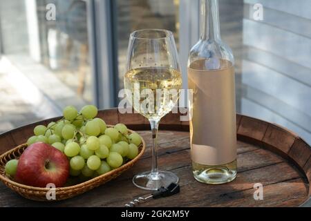 Ein Glas Weißwein mit Trauben auf einem Fass. Weißwein Riesling, aus weißen Trauben Stockfoto