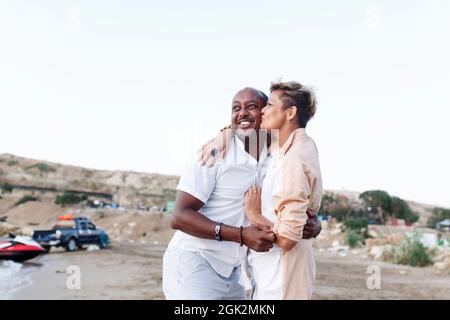 Gemischtes rassenlächelndes Paar, das im Urlaub genießt, Tourist, der Spaß am Strand hat, Vielfalt und Liebeskonzept. Stockfoto