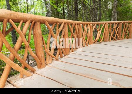 Geländer einer hölzernen Fußgängerbrücke in einem Sommerpark, Hintergrundbild Stockfoto