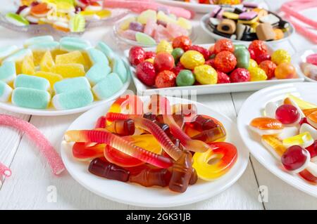 Verschiedene leckere bunte Gummy Bonbons auf Tellern. Vertikale Ansicht Stockfoto