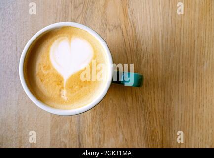 Kaffeegetränk mit Schaum, Latte oder Cappuccino. Keramikbecher mit Kaffee und Herzform, Draufsicht. Café-Innenausstattung Stockfoto