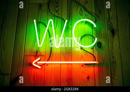 WC-Neonschild an der Holzwand. Toilette, Neon-Pointer für die Toilette Stockfoto