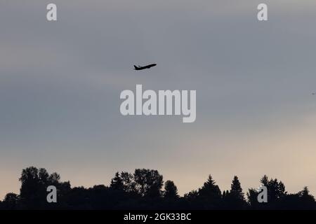 Doppeldecker, die hoch oben am Himmel flogen, schilhouetteten vor einem Sonnenuntergang Stockfoto