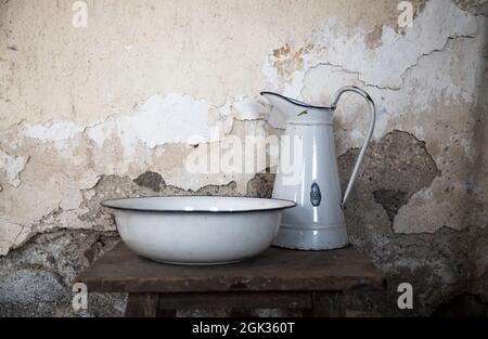 Altes Wasserbecken und Krug auf Holztisch an der Wand Stockfoto