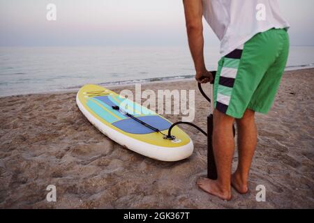 Nahaufnahme des Mannes bereitet sich auf die Paddelsurfen an einem Strand aufblasend supboard Stockfoto