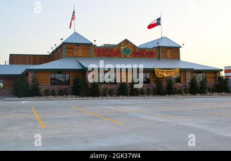 Humble, Texas USA 09-06-2019: Texas Roadhouse Steakhouse in Humble, TX mit einem Einstellungs-Schild vorne. Parkplatz im Vordergrund mit Flagge auf dem Dach. Stockfoto