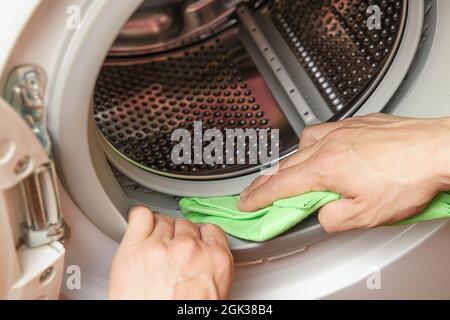 Feuchtigkeit von der Waschmaschinentrommel durch die Hand. Wartungskonzept der Waschmaschine Stockfoto