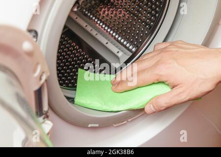 Feuchtigkeit von der Waschmaschinentrommel durch die Hand. Wartungskonzept der Waschmaschine Stockfoto