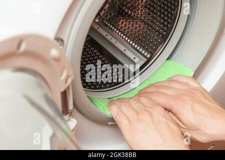 Feuchtigkeit von der Waschmaschinentrommel durch die Hand. Wartungskonzept der Waschmaschine Stockfoto