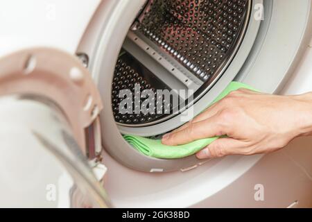 Feuchtigkeit von der Waschmaschinentrommel durch die Hand. Wartungskonzept der Waschmaschine Stockfoto