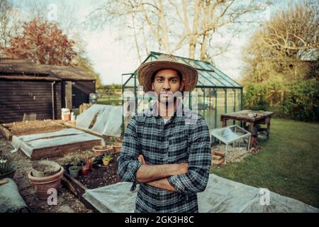 Gemischter männlicher Landwirt, der draußen beim grünen Haus steht Stockfoto