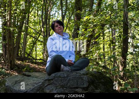 Ruhen Sie sich in der Natur mit einer jungen Frau in einem Wald aus Stockfoto