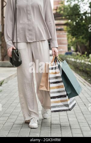 Nahaufnahme einer jungen Frau mit Einkaufstaschen, die im Freien durch die Stadt läuft Stockfoto