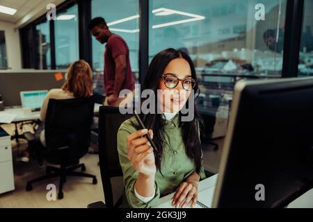 Schöne multiethnische Geschäftsfrau konzentriert sich während der Arbeit an wichtigen Bericht Essay für Chef im Büro sitzen Stockfoto
