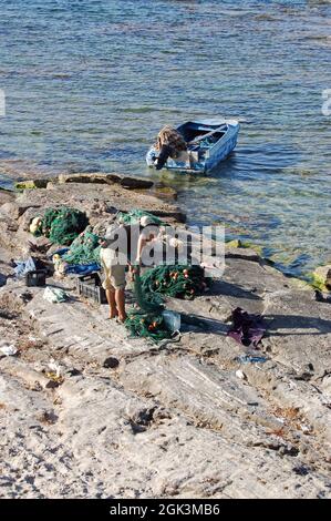 Ein eineinesischer Fischer, der seine Netze an der Küste des Mittelmeers in Khoms, Libyen, kontrolliert. Stockfoto