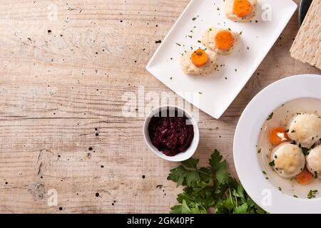 Traditionelle jüdische Matzah-Kugelsuppe, gefilter Fisch und Matzah-Brot auf Holztisch Stockfoto