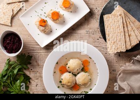 Traditionelle jüdische Matzah-Kugelsuppe, gefilter Fisch und Matzah-Brot auf Holztisch Stockfoto