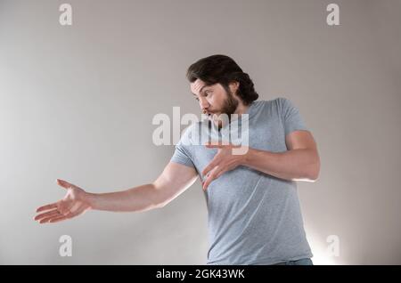 Der junge, bärtige, emotional überraschte, frustrierte und verwirrte Mann, isoliert auf grauem Studiohintergrund. Stockfoto