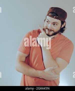 Junger hübscher kaukasischer Mann mit Bart und Hut, fröhlich mit einem Lächeln im Gesicht, das mit Hand und Finger zur Seite zeigt und glücklich und natürlich ist Stockfoto