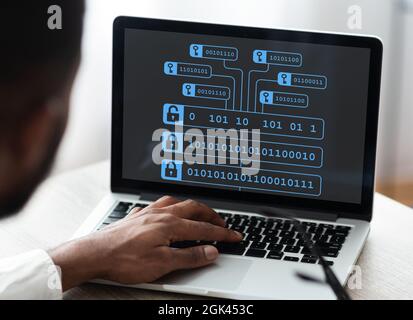 Zugeschnittenes, tausendjähriges afroamerikanisches Geschäftsmannes, das auf einem Laptop mit doppelter Belichtung und Blockchain-Code auf einem Laptop arbeitet Stockfoto