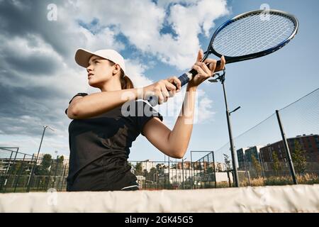 Schöner Tennisspieler, der im Freien eine Rückhand oder einen Volley schoss, in der Nähe des Netzes in Bewegung Stockfoto