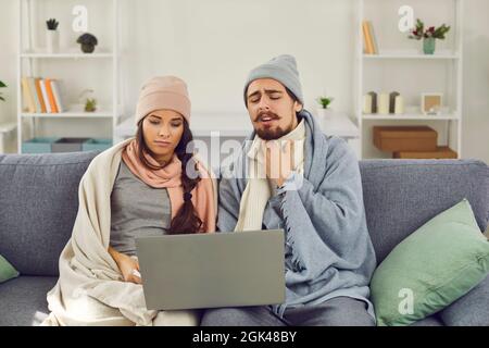 Paar, an Grippe erkrankt, auf der Couch sitzend und medizinische Beratung per Videoanruf Stockfoto