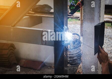 Mann Schweißer, der eine Metalltreppenkonstruktion in einem Wohngebäude mit einer Schweißmaschine macht. Stockfoto