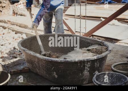 Arbeiter Mann Hausbauer mischen Mörtel aus einem Trog in Eimer Stockfoto