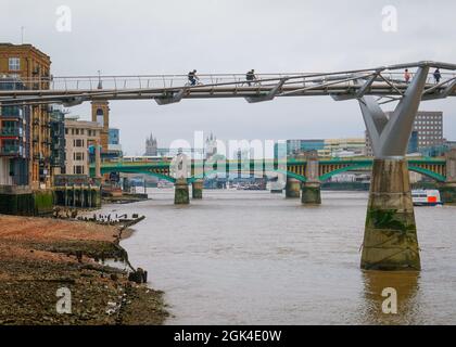 London, September 2021: Zwei Menschen blicken von der Millennium Bridge über die Themse auf die Londoner Brücken Stockfoto