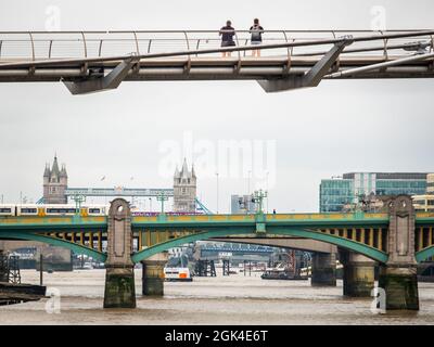 London, September 2021: Zwei Menschen blicken von der Millennium Bridge über die Themse auf die Londoner Brücken Stockfoto