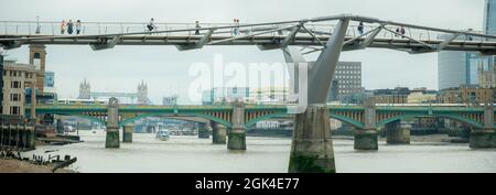 London, September 2021: Zwei Menschen blicken von der Millennium Bridge über die Themse auf die Londoner Brücken Stockfoto
