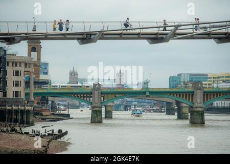 London, September 2021: Zwei Menschen blicken von der Millennium Bridge über die Themse auf die Londoner Brücken Stockfoto