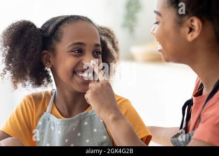 Nahaufnahme einer schwarzen Dame, die ihre Töchternase mit Mehl befleckt hat Stockfoto