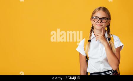 Nachdenkliches Teenager blondes Schulmädchen, kaukasische Frau mit Zöpfen, Rucksack in Brille denkt, schaut auf den Kopierraum Stockfoto