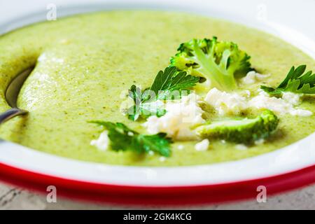 Brokkoli-Suppenpüree mit Feta-Käse auf weißem Teller, Nahaufnahme. Kochen gesundes Essen Konzept. Stockfoto