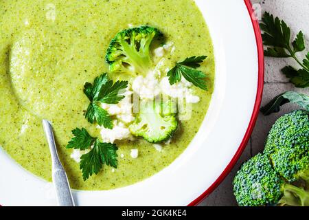Brokkoli-Suppenpüree mit Feta-Käse auf weißem Teller, Nahaufnahme. Kochen gesundes Essen Konzept. Stockfoto