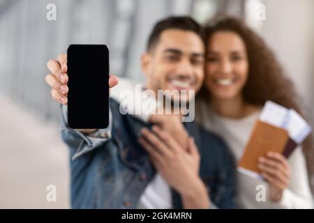 Glückliches Arabisches Paar Zeigt Smartphone Mit Leerem Schwarzen Bildschirm Im Flughafen Stockfoto