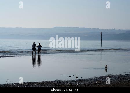 Pärchen, die am Filey Beach an der Ostküste von North Yorkshire spazieren, beschäftigt mit Urlaubern, Nordengland, Großbritannien Stockfoto