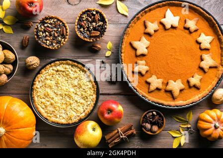 Thanksgiving Herbstkuchen auf Holzhintergrund. Herbst hausgemachte Kürbis-, Apfel- und Pekannüssen und Zutaten für die Herbstferien. Stockfoto