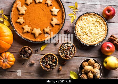 Thanksgiving Herbstkuchen auf Holzhintergrund. Herbst hausgemachte Kürbis-, Apfel- und Pekannüssen und Zutaten für die Herbstferien. Stockfoto