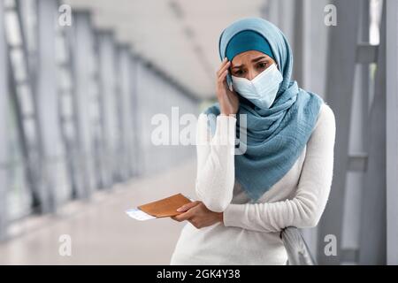 Stornierter Flug. Deprimierte Islamische Frau In Maske Und Hijab Im Flughafen Stockfoto