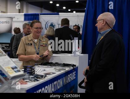 NATIONAL HARBOUR, MD. (3. August 2021) LT. Comm Lynne Hatton spricht mit einem Teilnehmer am Naval Information Warfare Stand während der Sea-Air-Space 2021 Ausstellung. Die Sea-Air-Space-Ausstellung ist eine jährliche Veranstaltung, bei der wichtige militärische Entscheidungsträger, der US-Verteidigungsstützpunkt und private US-Unternehmen zu einer innovativen und lehrreichen maritimen Veranstaltung zusammenkommen. Stockfoto