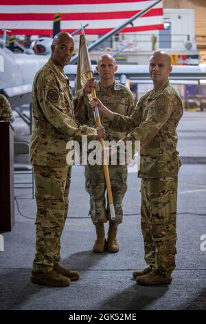 US Air Force Maj. David T. Brown (rechts), scheidender 41. Expeditionary Electronic Combat Squadron Commander, gibt das Kommando ab, indem er den Staffelführer an LT. Col. Brian L. Hardeman, den stellvertretenden Kommandanten der 380. Expeditionary Maintenance Group, während der EECS-Befehlswechsel-Zeremonie auf dem Luftwaffenstützpunkt Al Dhafra, Vereinigte Arabische Emirate, übergibt. August 3, 2021. Die Übergabe der Führung symbolisiert eine Übertragung des Kommandos, der 41. EECS von Brown an LT. Col. Joseph Clancy. Stockfoto