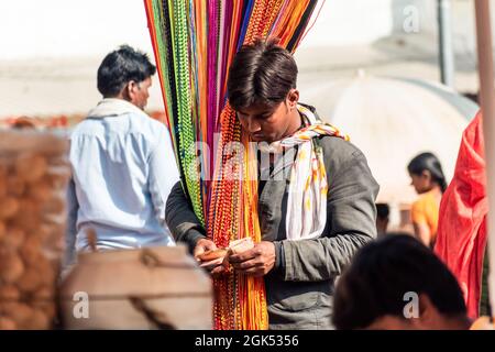 Orchha, Madhya Pradesh, Indien - 2019. März: Ein Straßenhändler, der bunte Textilien auf einem überfüllten Markt in Orchha verkauft. Stockfoto